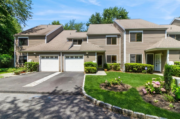 View of front of property with a garage, driveway, a shingled roof, and a front yard