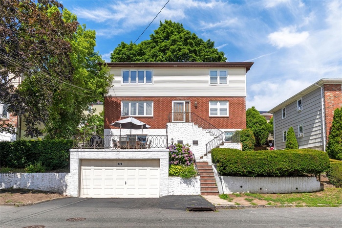 View of front of home featuring stairs, asphalt driveway, a 2 car garage, and brick siding