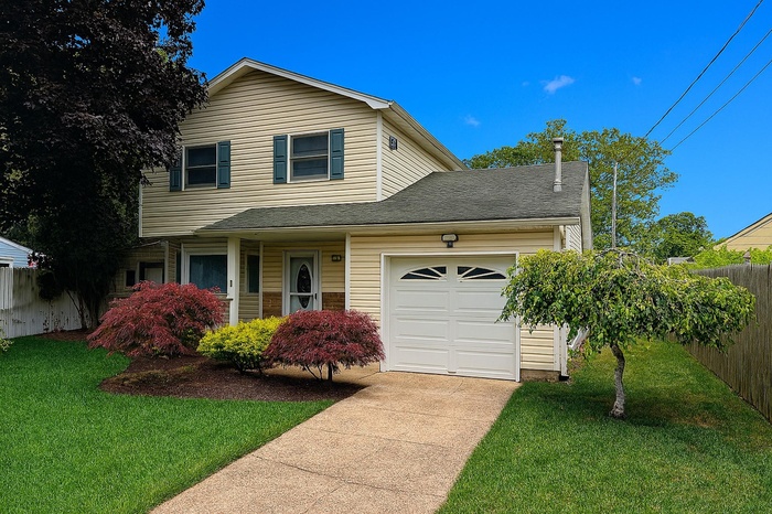 Traditional-style house featuring driveway, an attached garage, and roof with shingles