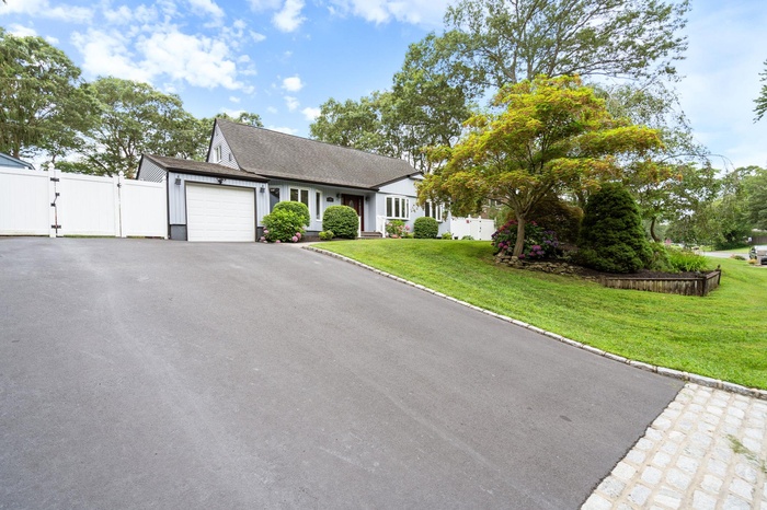 Single story home with a gate, an attached garage, driveway, and a shingled roof