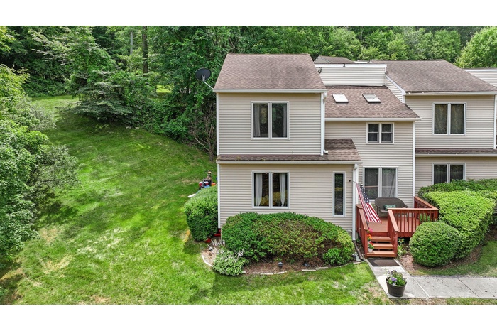 View of front of home featuring a front yard, a wooden deck, and roof with shingles