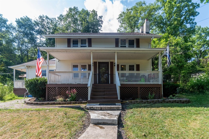 View of front of home featuring a porch, a front yard, and a chimney