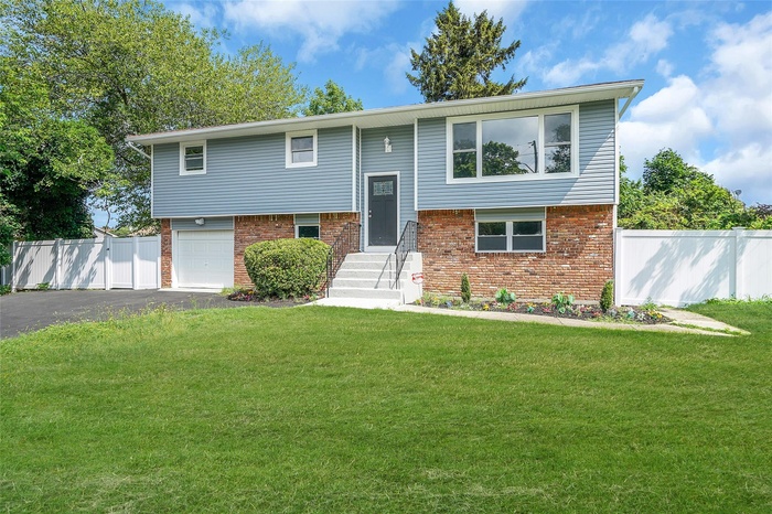 Raised ranch featuring driveway, brick siding, and a garage