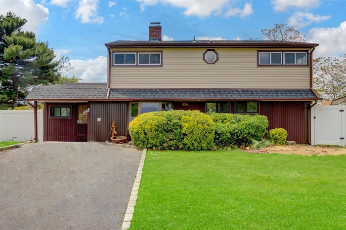 View of front of home featuring a chimney, a shingled roof, asphalt driveway, and a gate