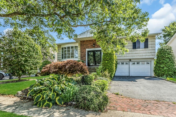 View of front of house with driveway, a garage, and brick siding