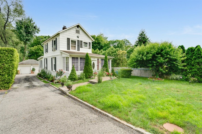 View of front of property featuring an outbuilding, a chimney, and a detached garage