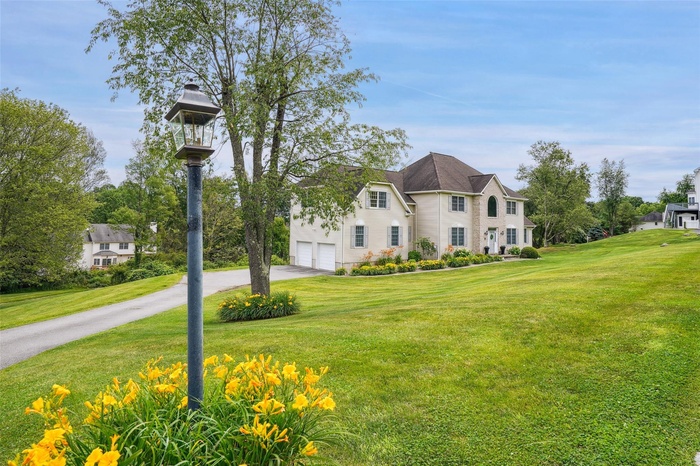 View of front of property featuring asphalt driveway and a front lawn