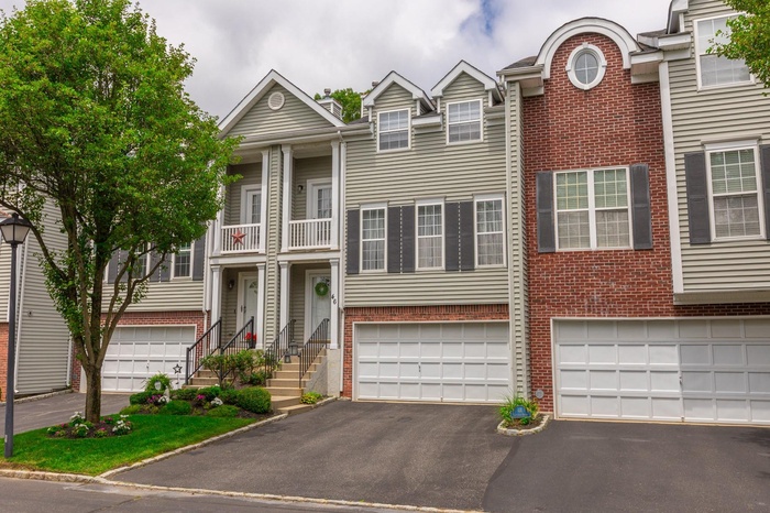 View of front of home featuring brick siding, a balcony, driveway, and an attached garage