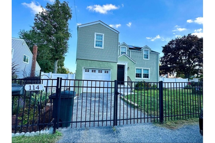 View of front of house with an attached garage, stucco siding, and a gate