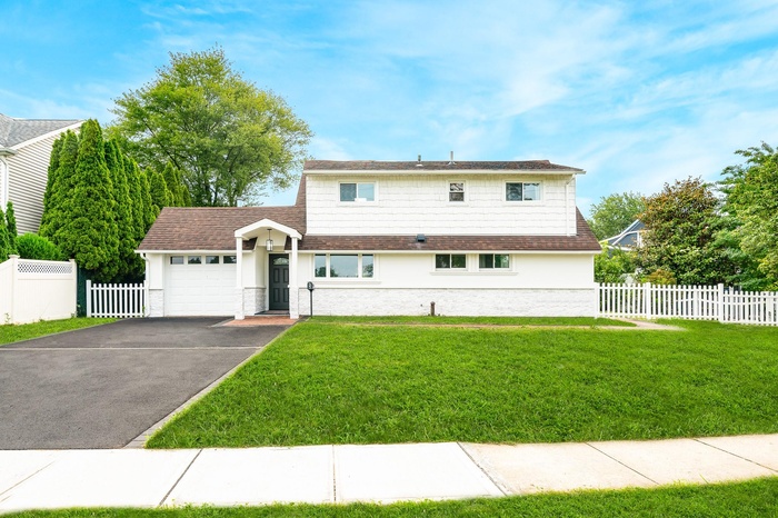 View of front of property with asphalt driveway, an attached garage, roof with shingles, and stucco siding