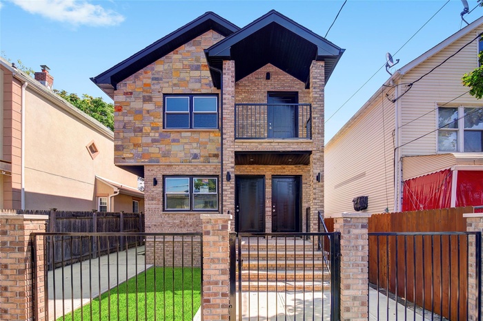 View of front facade featuring a balcony, a gate, a fenced front yard, and brick siding
