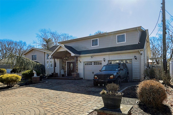 View of front of home with a garage and decorative driveway