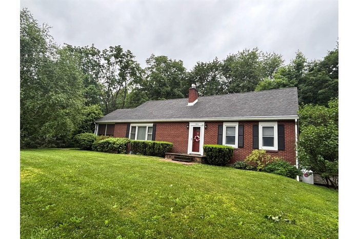 Single story home featuring brick siding, a chimney, and a front lawn