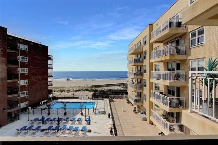 Community pool featuring view of water and beach