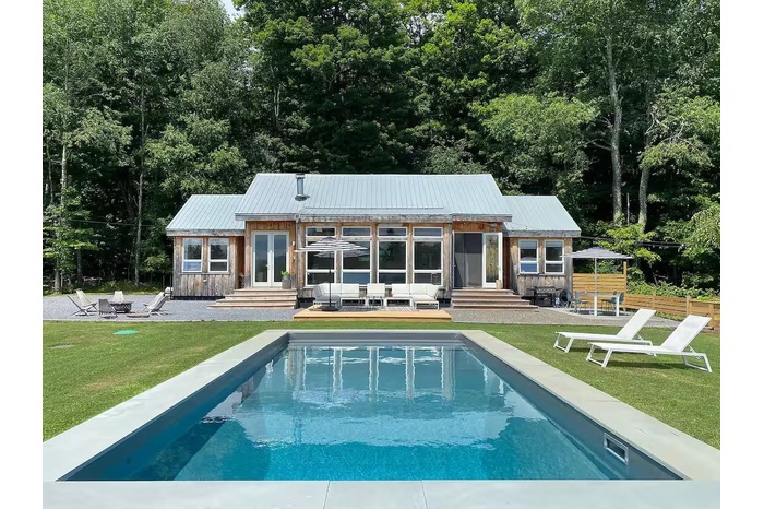 Front of property with a lawn, an outdoor pool, a patio area, an outdoor living space with a fire pit, and entry steps