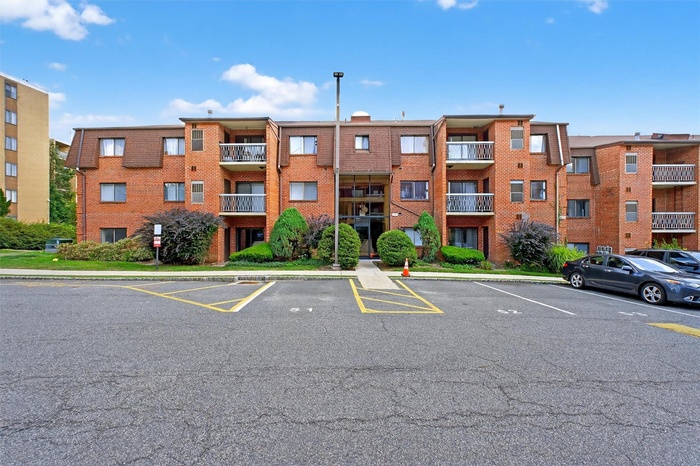 View of apartment building / complex featuring uncovered parking