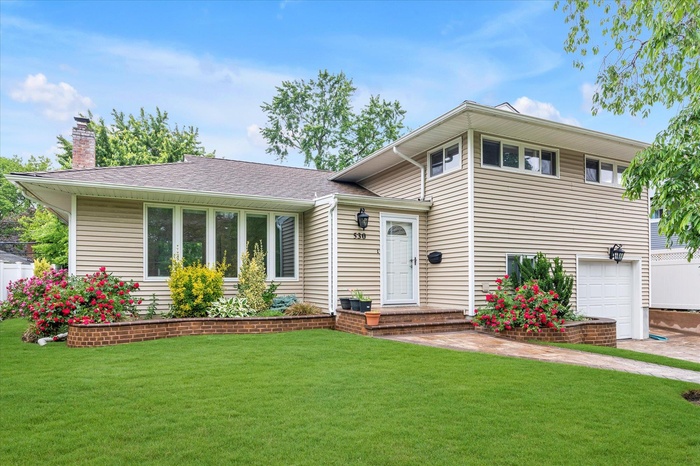 Split level home featuring  new paved walkway, new new vinyl siding, new Anderson energy windows & door, garage, and a shingled roof.