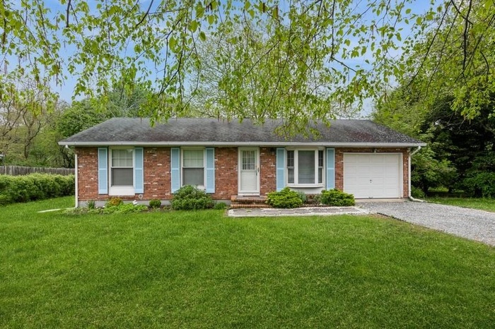 Ranch-style house featuring driveway, an attached garage, and brick siding