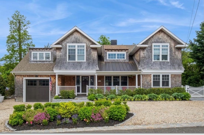 Shingle-style home featuring a gate, a garage, a standing seam roof, fence, and covered porch