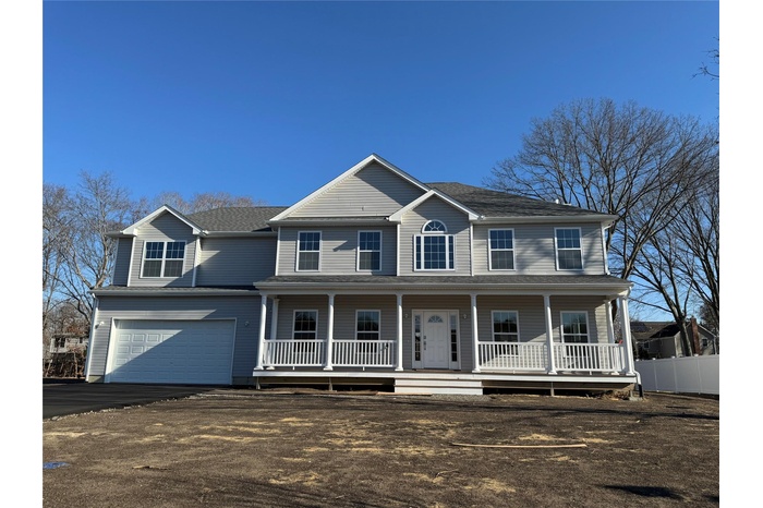 Colonial home featuring a porch, an attached garage, driveway, and fence