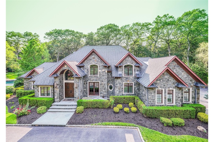 French country home with stone siding, a high end roof, and view of scattered trees