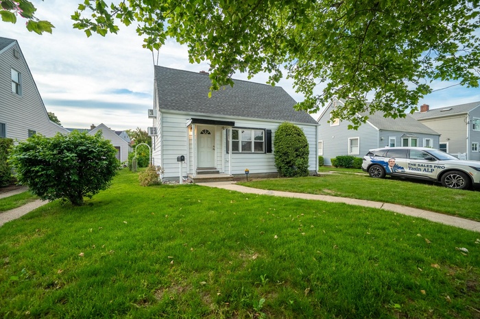 View of front of home featuring a front lawn and roof with shingles