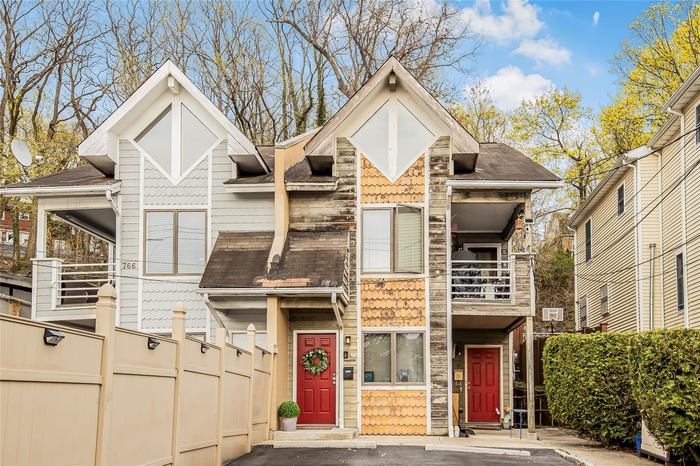 View of front of home featuring fence, a balcony, and roof with shingles