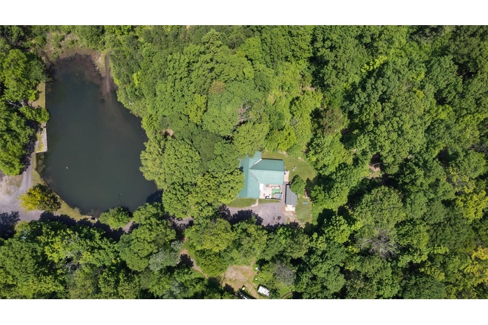 Aerial overview of property's location with a nearby body of water and a heavily wooded area