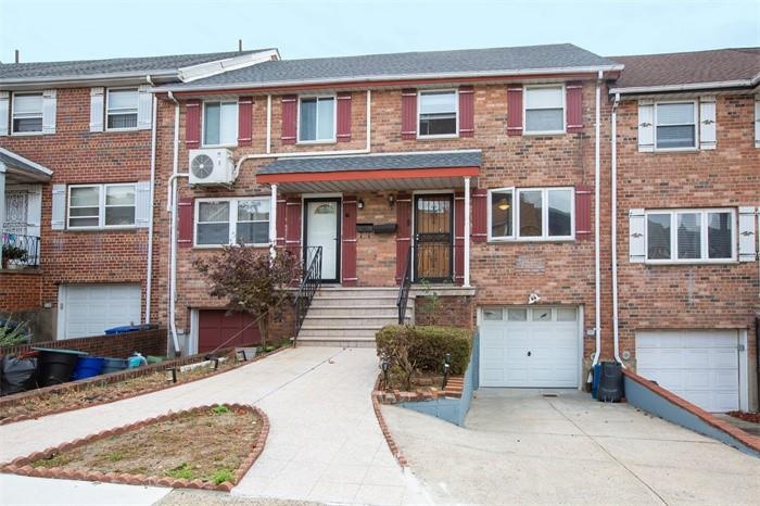 Townhome / multi-family property with a garage, driveway, a cooling unit, and brick siding