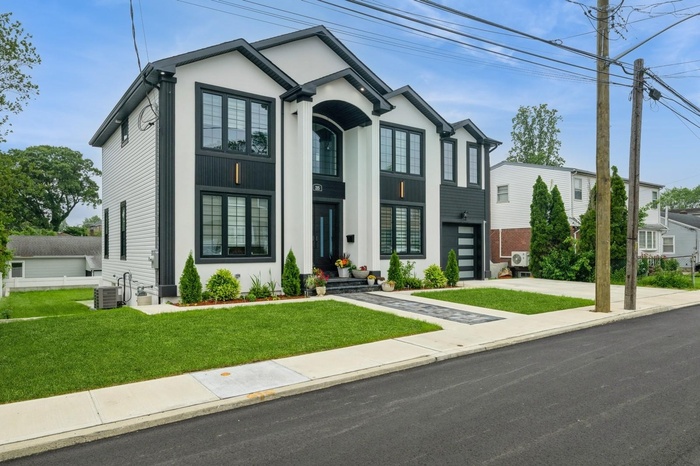 View of front of home with a front lawn, driveway, an attached garage, and stucco siding