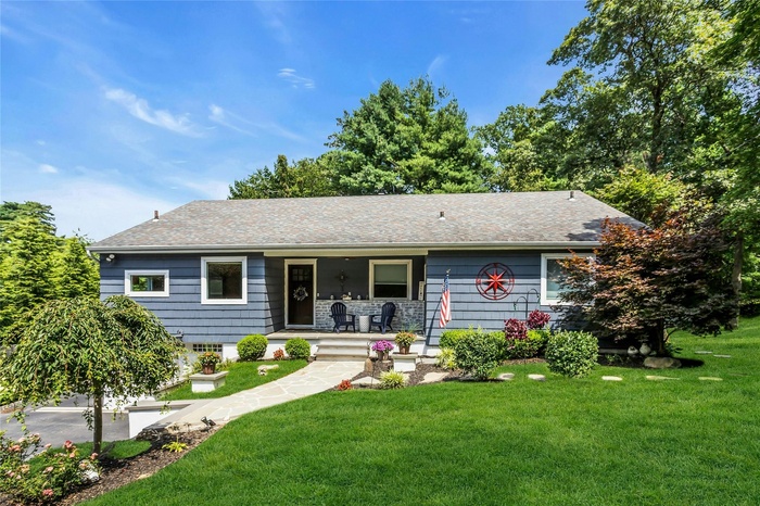Ranch-style house featuring a porch, roof with shingles, and a front yard