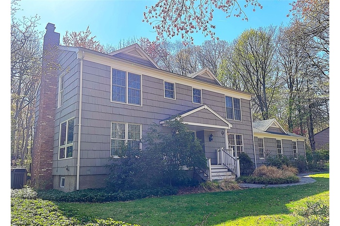 View of front of house featuring a chimney, a front lawn, and central air condition unit