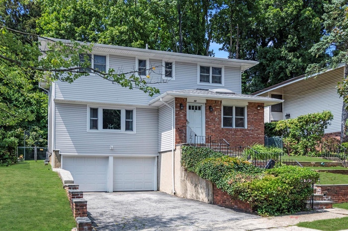 View of front facade featuring an attached garage, asphalt driveway, and brick siding