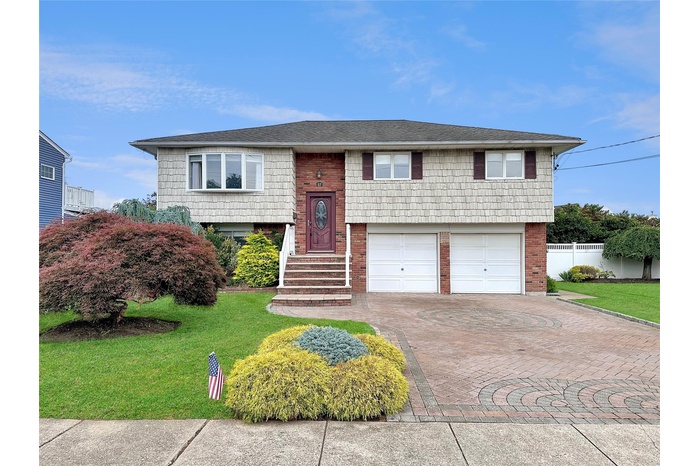 Bi-level home with decorative driveway, brick siding, and a garage