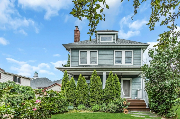 Traditional style home featuring a chimney, a porch, roof with shingles, and a front lawn