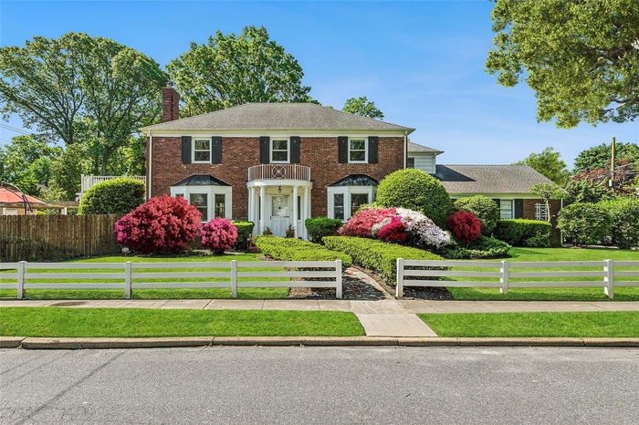 Colonial inspired home with a chimney and brick siding