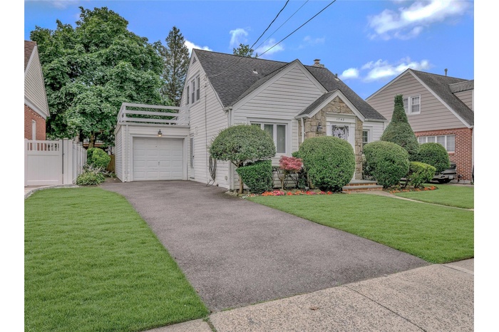 Bungalow-style house with driveway, a garage, roof with shingles, a chimney, and stone siding