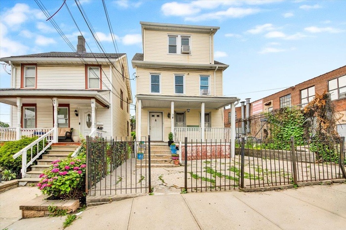 View of front of property featuring covered porch, a fenced front yard, a gate, and stairs
