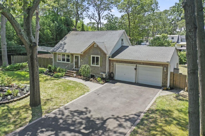 View of front of house featuring a shingled roof, asphalt driveway, and an attached garage