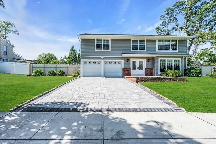 Traditional-style home featuring french doors, decorative driveway, a garage, and brick siding