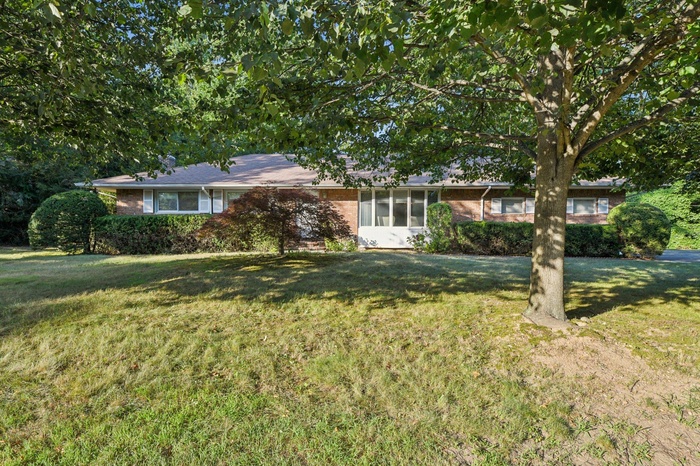 Ranch-style house featuring brick siding and a front lawn