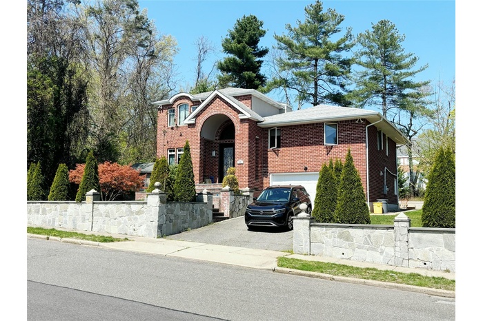View of front facade with a garage, driveway, and brick siding