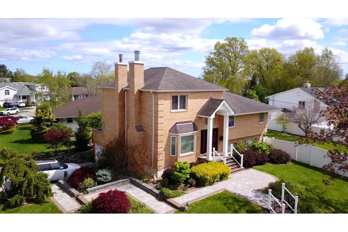 Traditional-style home featuring a chimney, brick siding, a shingled roof, and a residential view