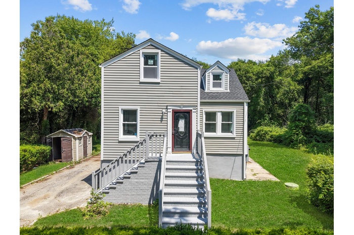 View of front of house featuring a shed and a front lawn