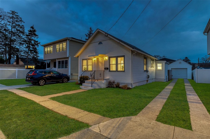 Bungalow-style home with a garage, driveway, and an outbuilding