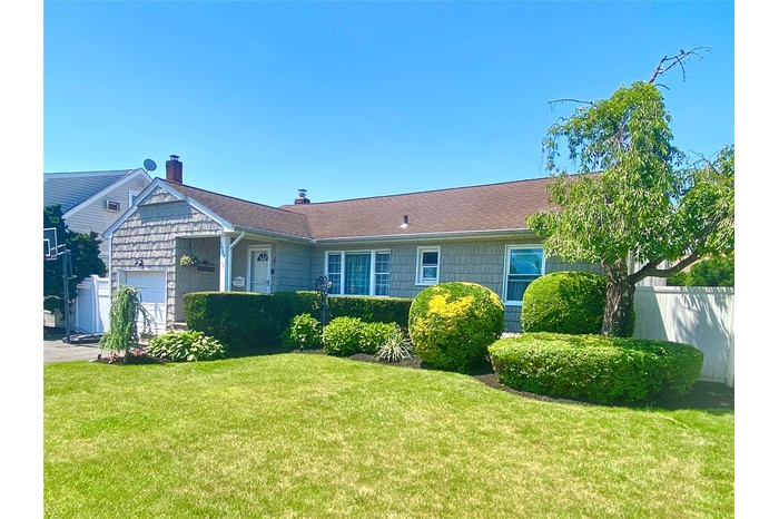 View of front of house featuring an attached garage, a shingled roof, and a chimney