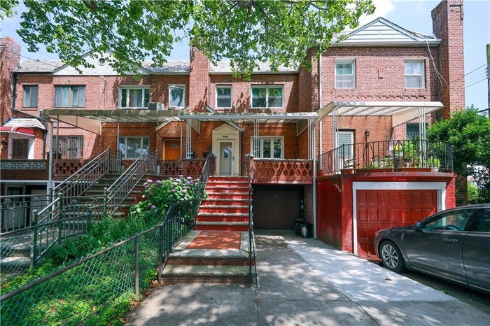 View of property featuring concrete driveway, an attached garage, brick siding, and stairs