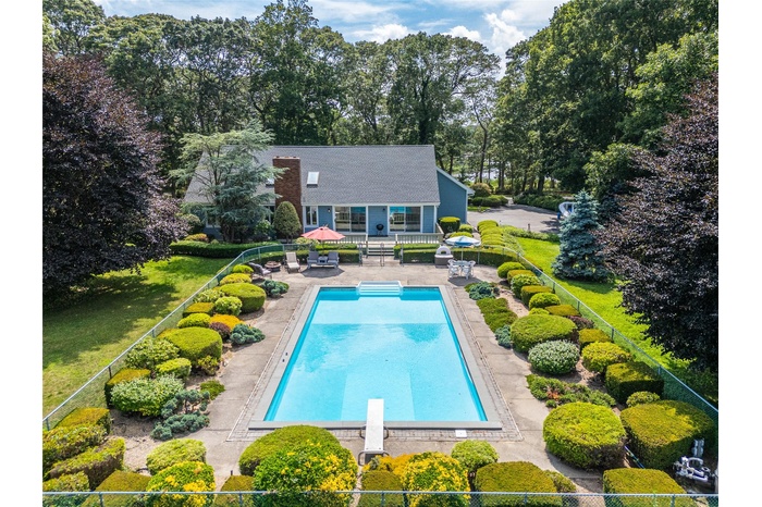 Swimming pool with a diving board, a patio area, peek-a-boo view of water across the street