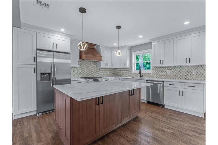 Kitchen with appliances with stainless steel finishes, custom range hood, dark wood-style flooring, a center island, and recessed lighting