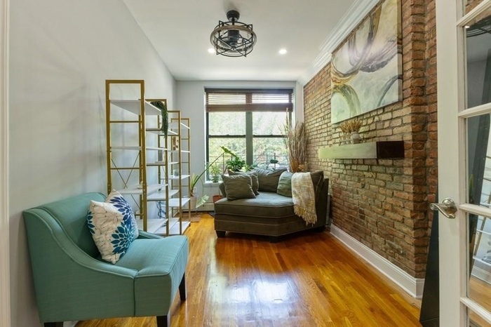 Sitting room with brick wall, wood finished floors, and recessed lighting